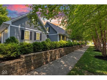 Charming home with beautiful landscaping, stone retaining wall, and gray siding with black shutters at 900 W Busby St, Lebanon, IN 46052