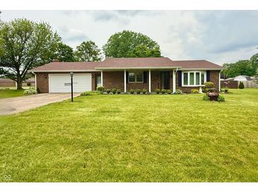 Charming brick home featuring a well-manicured lawn, attached garage, and decorative landscaping at 9099 Ne Oak St, Alexandria, IN 46001