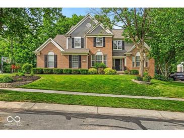 Charming brick two-story home with well-manicured lawn, lush landscaping, and classic architectural details at 9834 Belcrest Ln, Indianapolis, IN 46256