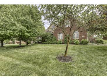 Beautiful two-story brick home featuring a manicured lawn, mature trees, and charming architectural details at 2553 Forest Hills Blvd, Greenwood, IN 46143