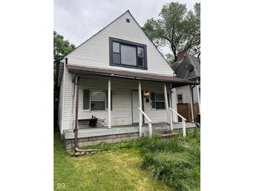 Exterior front view of a two-story home with a small porch and overgrown landscaping at 319 S Temple Ave, Indianapolis, IN 46201