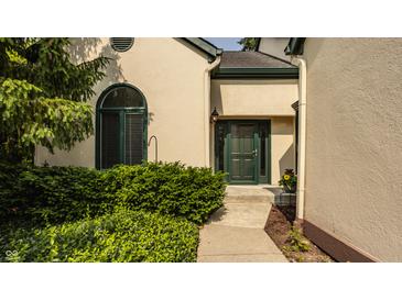 Charming home exterior with a green front door, arched window, and lush landscaping at 4428 Edinburgh Pt, Indianapolis, IN 46228