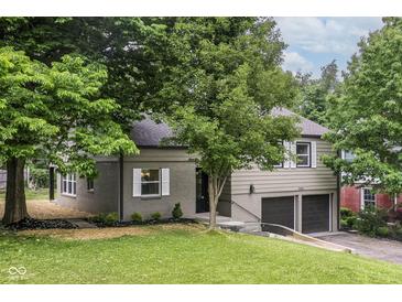 Charming exterior view with a two-car garage, dark roof, and well-maintained lawn at 5884 Compton St, Indianapolis, IN 46220