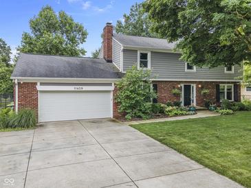 Charming two-story home featuring a brick and siding facade, attached two-car garage and beautiful landscaping at 11409 Haverstick Rd, Carmel, IN 46033