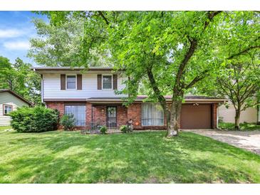 Charming two-story home featuring a brick facade, complemented by a well-maintained lawn and mature trees at 3425 Ireland Dr, Indianapolis, IN 46235