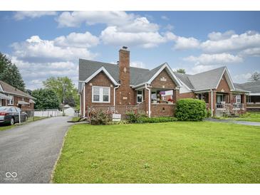 Charming brick home featuring a well-manicured lawn, inviting front porch, and classic architectural details at 5435 E 10Th St, Indianapolis, IN 46219