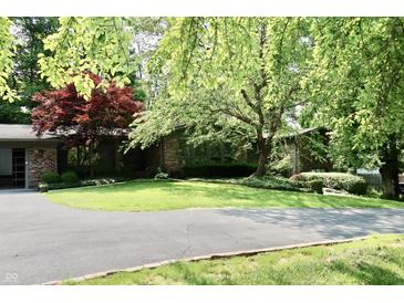 Charming single-story brick home with a well-manicured lawn, mature trees, and circular driveway at 6519 Creekside Ln, Indianapolis, IN 46220