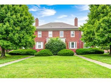 Charming two-story brick home with mature trees and a lush green lawn under a blue sky at 8436 E 56Th St, Indianapolis, IN 46216