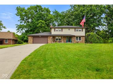 Charming two-story home featuring a brick facade, attached garage, and expansive green lawn at 955 Wood Creek Pl, Greenwood, IN 46142
