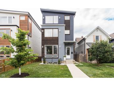 Modern home showcasing a stylish exterior with blue and wood accents and a well-manicured front lawn at 1452 Fletcher Ave, Indianapolis, IN 46203