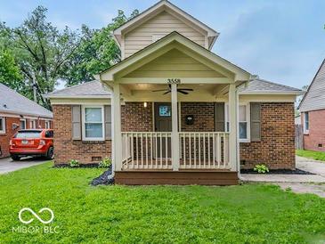 Charming brick home featuring a cozy front porch, landscaped lawn, and classic architectural details at 3558 N Gladstone Ave, Indianapolis, IN 46218