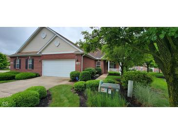 Charming brick home with a two-car garage and inviting landscaping with lush green bushes at 5189 Bally Bunion Dr, Avon, IN 46123