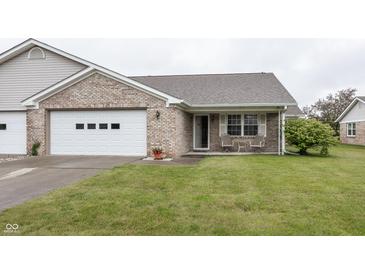 Charming brick home with a two-car garage and a cozy front porch seating area at 7632 Sea Crest N Way, Noblesville, IN 46062