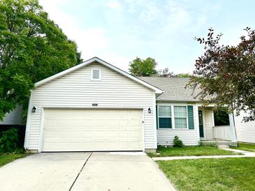 Charming single-story home featuring a two-car garage, manicured lawn, and lush surrounding trees at 10922 Snowdrop Way, Indianapolis, IN 46235