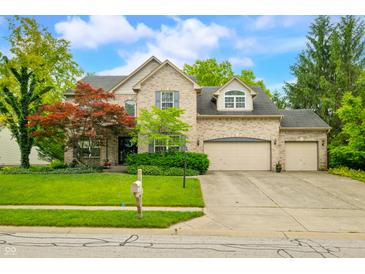 Charming two-story brick home with a well-manicured lawn and mature trees on a sunny day at 1245 Elm Grove Ln, Greenwood, IN 46143