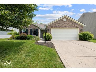 Charming single-story brick home featuring an attached two car garage, a manicured lawn and mature trees at 5967 Peregrine Blvd, Indianapolis, IN 46228