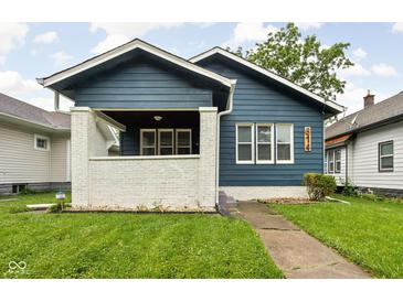 Charming blue home featuring a quaint front porch, lush lawn, and inviting curb appeal at 614 N Drexel Ave, Indianapolis, IN 46201