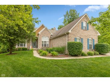 Charming brick home with manicured lawn, complemented by lush landscaping and blue shutters at 7818 Fawnwood Dr, Indianapolis, IN 46278