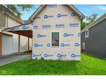 Exterior view of home featuring protective builder's wrap, a window, and a tidy lawn at 1917 Union St, Indianapolis, IN 46225