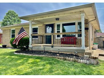 Inviting front porch with a red bench, American flag, and well-manicured lawn at 419 N 14Th Ave, Beech Grove, IN 46107