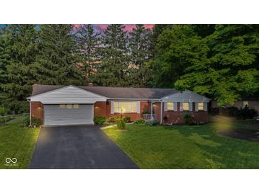 Dusk view of a red brick home with an attached garage, highlighting the well-lit exterior and inviting ambiance at 703 Chapel Hill W Dr, Indianapolis, IN 46214