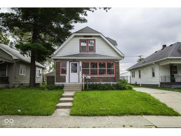 Charming home featuring a well-manicured lawn, brick accents, and a welcoming entrance at 1115 N Kealing Ave, Indianapolis, IN 46201