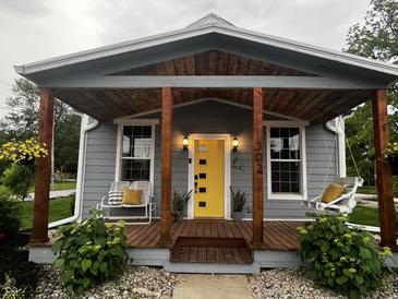 Charming home featuring a covered front porch with seating and a bright yellow door at 302 Penn St, Westfield, IN 46074