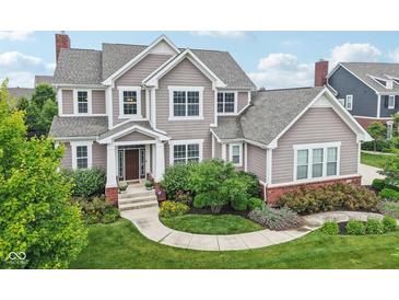 Charming two-story home with landscaped yard, a brick foundation, and neutral toned siding at 10806 Solis Cir, Fishers, IN 46038