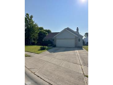 Charming home featuring a well-maintained lawn, mature trees, and a convenient two-car garage at 12307 Chiseled Stone Dr, Fishers, IN 46037