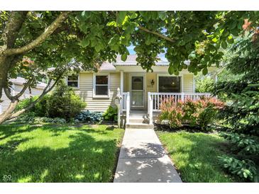 Charming single-story home with a cozy front porch, lovely landscaping, and a well-maintained lawn at 1411 N Kenmore Rd, Indianapolis, IN 46219