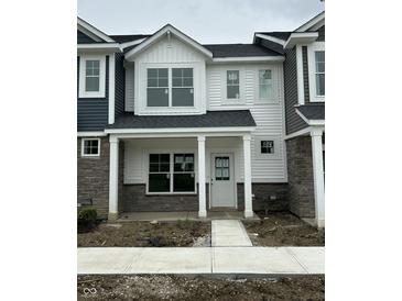 Charming townhome with white siding, stone accents, covered porch, and sidewalk at 19571 Grassy Branch Dr, Westfield, IN 46074