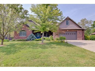 Inviting brick home featuring a blue door and a well-manicured lawn at 214 W Stoney Trl, Greenfield, IN 46140