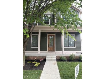 Charming two-story home with a covered front porch, complemented by dark green siding and beautifully landscaped flowerbeds at 2148 N Pennsylvania St, Indianapolis, IN 46202