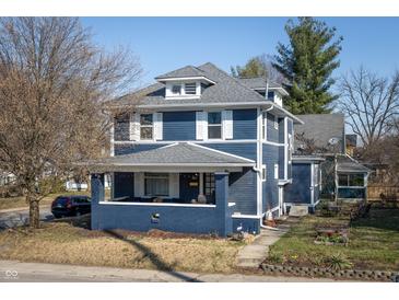 Charming two-story home features a covered front porch, gray roof, and a blue exterior at 6101 Broadway St, Indianapolis, IN 46220