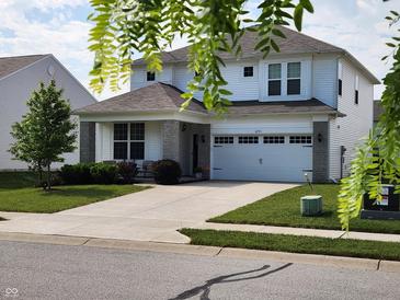 Charming two-story home with a well-manicured lawn, stone accents, and a wide driveway at 6731 Keepsake Dr, Whitestown, IN 46075
