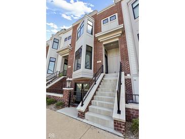 Inviting brick townhome exterior featuring a staircase leading to the front door and a bay window at 711 E 16Th St, Indianapolis, IN 46202
