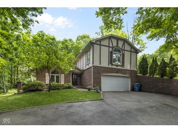 Charming two-story Tudor-style home with brick and siding, lush landscaping, and a two-car garage at 8310 Fall Creek Rd, Indianapolis, IN 46256