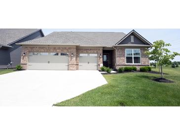 Charming brick home boasts a well-manicured lawn, two-car garage, and inviting front entrance at 9671 Holborn Ave, McCordsville, IN 46055