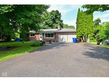 Charming single-story brick home with a spacious driveway and mature trees in a serene neighborhood at 11522 Newport Dr, Indianapolis, IN 46236