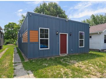 Charming home featuring vertical siding, a red front door, and complemented by landscaped surroundings at 1409 N Grant Ave, Indianapolis, IN 46201