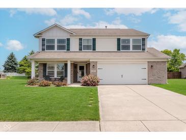 Charming two-story home featuring a well-manicured lawn, attached garage, and inviting front porch with decorative landscaping at 985 Farmington Trl, Brownsburg, IN 46112