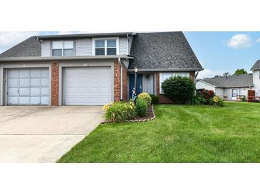 Charming townhome with a lush green lawn, colorful flower beds, and an attached one-car garage at 1124 Paradise Ct # B, Greenwood, IN 46143