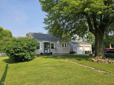 Charming single-story home with a well-maintained lawn, mature trees, and a detached two-car garage at 1510 Chester St, Anderson, IN 46012
