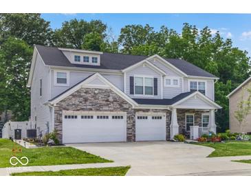Charming two-story home with stone accents, a two-car garage, a beautifully landscaped yard, and an inviting front porch at 210 Lynnette Way, Cumberland, IN 46229