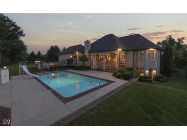 Gorgeous backyard with a luxurious pool, slide, patio, and outdoor fireplace for elegant entertaining at 3795 Claybrook Ct, Bargersville, IN 46106