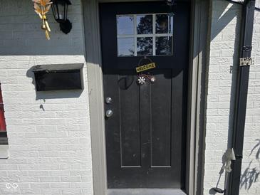 Inviting front door with charming welcome sign and brick exterior, adding a touch of warmth and character at 6508 Meadowlark Dr, Indianapolis, IN 46226