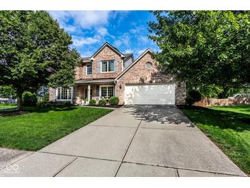 Traditional brick home with a well-manicured lawn, long driveway, and mature trees under a blue sky at 9740 Logan Ln, Fishers, IN 46037