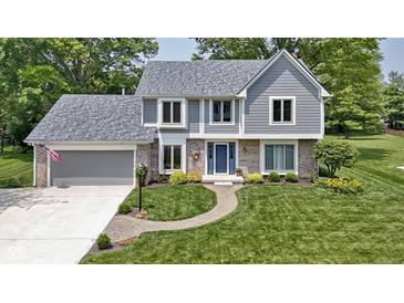 Charming two-story home featuring a manicured lawn, brick accents, and a welcoming blue front door at 15120 Romalong Ln, Carmel, IN 46032