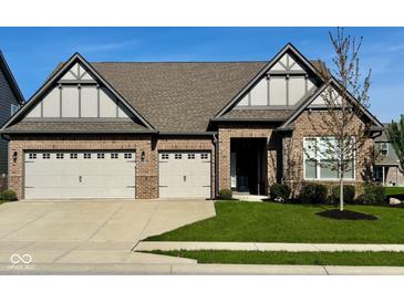 Beautiful brick home featuring a three-car garage and manicured lawn at 17324 Americana Crossing Xing, Noblesville, IN 46060