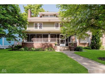 Charming two-story home with a screened-in porch, lush lawn, and mature trees, providing curb appeal at 3246 N New Jersey St, Indianapolis, IN 46205